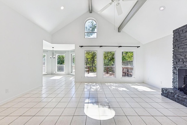 unfurnished living room featuring a stone fireplace, a wealth of natural light, beamed ceiling, and ceiling fan