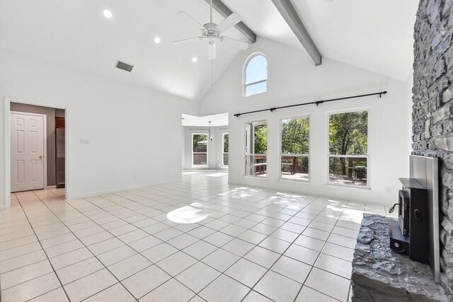 unfurnished living room with a wood stove, high vaulted ceiling, ceiling fan, light tile patterned floors, and beam ceiling