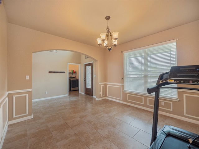 exercise area with light tile patterned floors and a chandelier