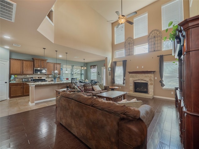 living room with a towering ceiling, hardwood / wood-style floors, and ceiling fan