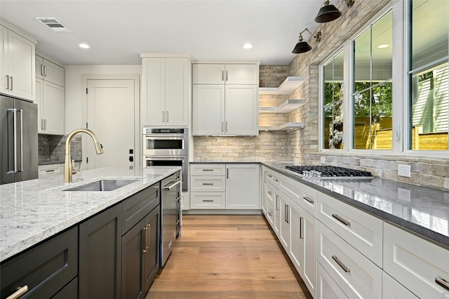 kitchen with sink, white cabinets, light hardwood / wood-style flooring, and stainless steel appliances