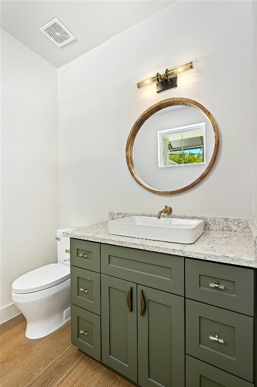 bathroom featuring wood-type flooring, toilet, and vanity