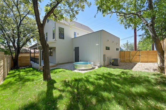 back of property with central AC unit and a yard