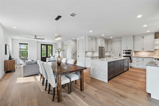 dining area featuring sink, light wood-type flooring, and beverage cooler