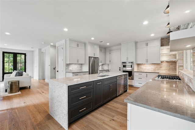 kitchen featuring sink, a center island with sink, white cabinets, and appliances with stainless steel finishes