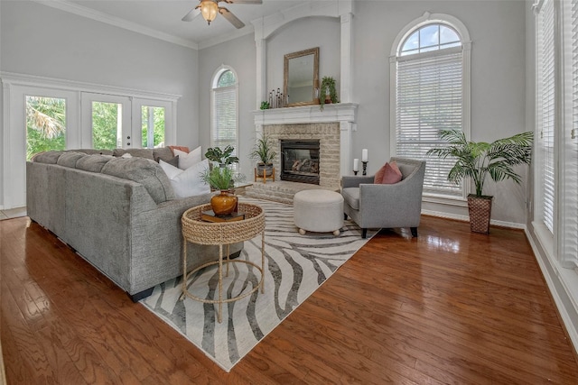 living room featuring a healthy amount of sunlight, ornamental molding, dark hardwood / wood-style flooring, and a brick fireplace