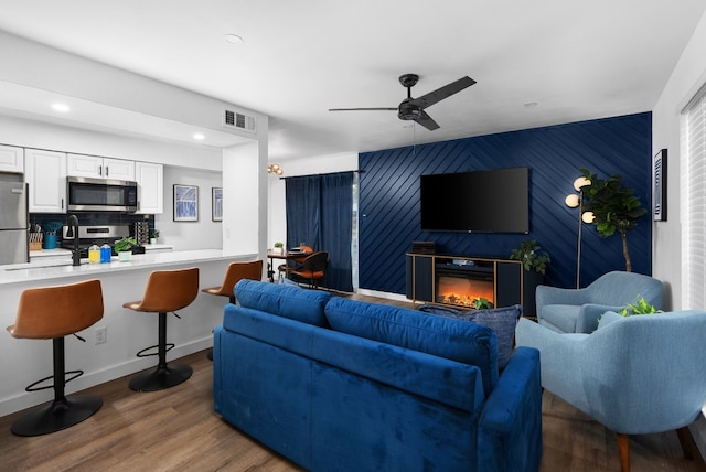 living room featuring ceiling fan and dark wood-type flooring