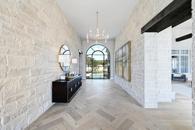 hallway with an inviting chandelier and light parquet flooring