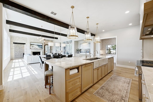 kitchen with a wealth of natural light, decorative light fixtures, sink, a large island, and high end stainless steel range