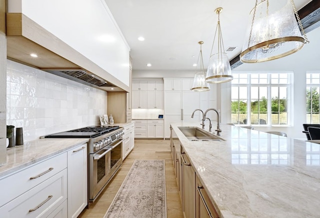 kitchen featuring range with two ovens, white cabinetry, light stone counters, hanging light fixtures, and decorative backsplash