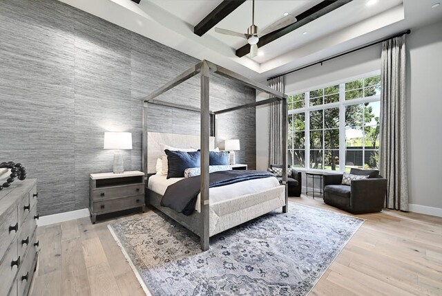 bedroom featuring ceiling fan, a towering ceiling, light hardwood / wood-style flooring, and beamed ceiling