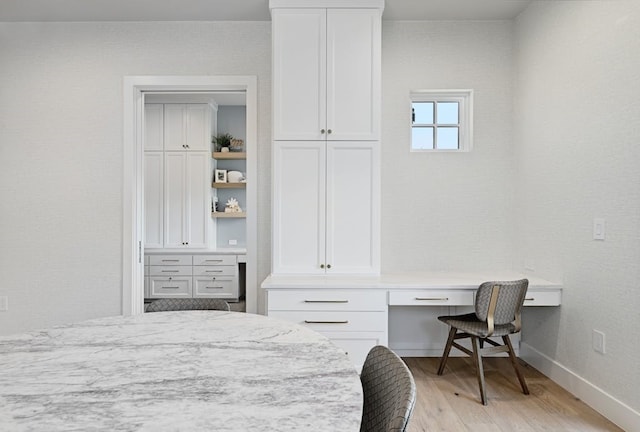 bedroom featuring built in desk and light hardwood / wood-style floors