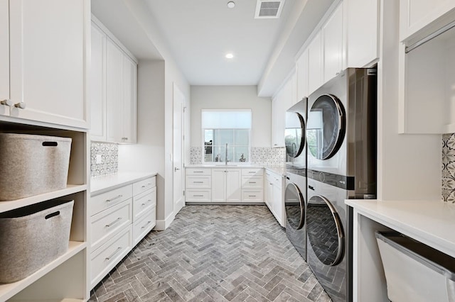 laundry room featuring cabinets, stacked washer / drying machine, and sink