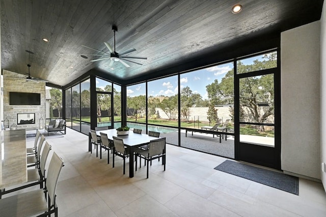 unfurnished sunroom with lofted ceiling, a fireplace, wooden ceiling, and ceiling fan