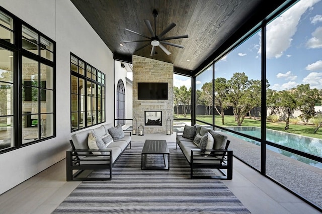 sunroom / solarium with ceiling fan, wooden ceiling, and an outdoor stone fireplace