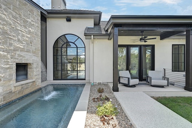 view of exterior entry with pool water feature, ceiling fan, and a patio