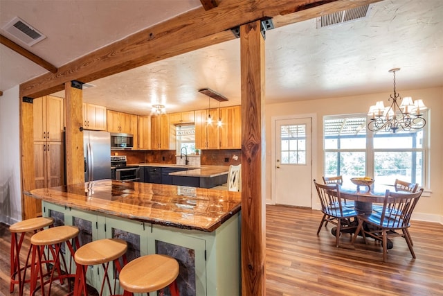 kitchen with a chandelier, hanging light fixtures, light hardwood / wood-style flooring, appliances with stainless steel finishes, and light brown cabinetry