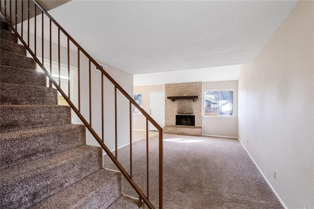 stairway with carpet, a textured ceiling, and a brick fireplace