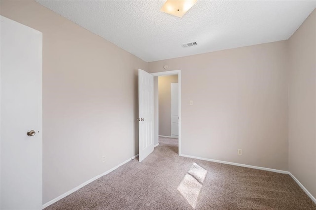 empty room with light carpet and a textured ceiling