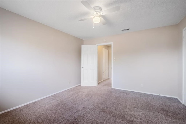 carpeted spare room featuring ceiling fan and a textured ceiling