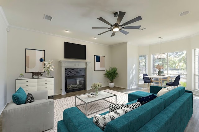 living room featuring light wood-type flooring, plenty of natural light, and crown molding