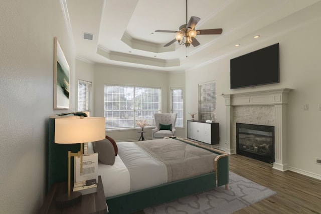 bedroom featuring wood-type flooring, a raised ceiling, crown molding, and ceiling fan