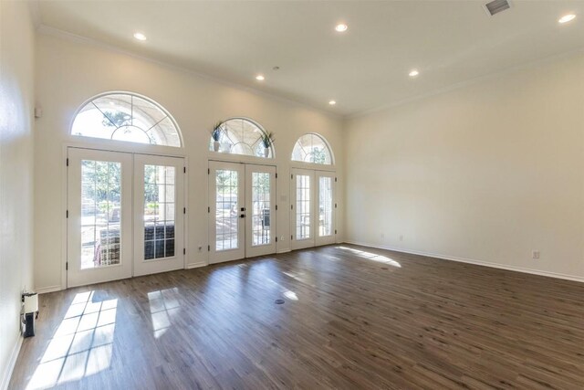 interior space with crown molding, a high ceiling, dark wood-type flooring, and french doors