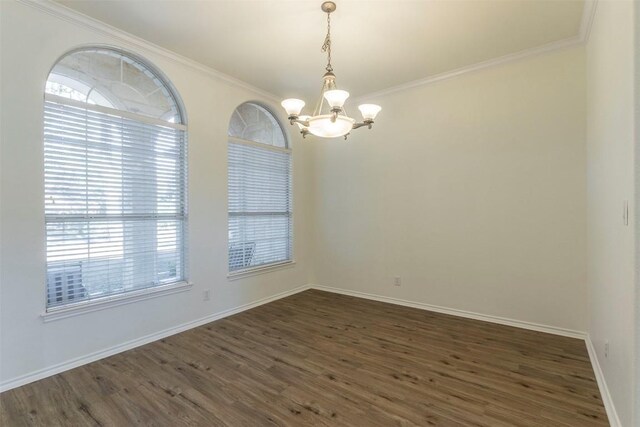 unfurnished room featuring ornamental molding, an inviting chandelier, and dark wood-type flooring