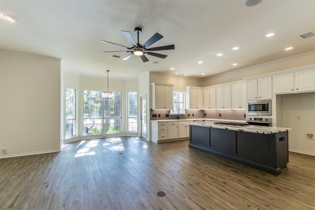 kitchen featuring white cabinets, a kitchen island, appliances with stainless steel finishes, crown molding, and dark hardwood / wood-style flooring