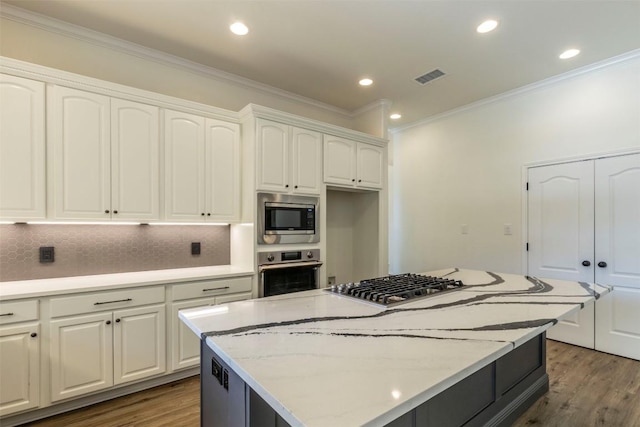 kitchen with visible vents, a kitchen island, crown molding, wood finished floors, and stainless steel appliances