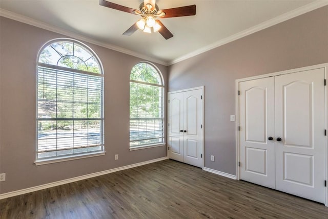 unfurnished bedroom featuring multiple closets, crown molding, baseboards, ceiling fan, and dark wood-style flooring