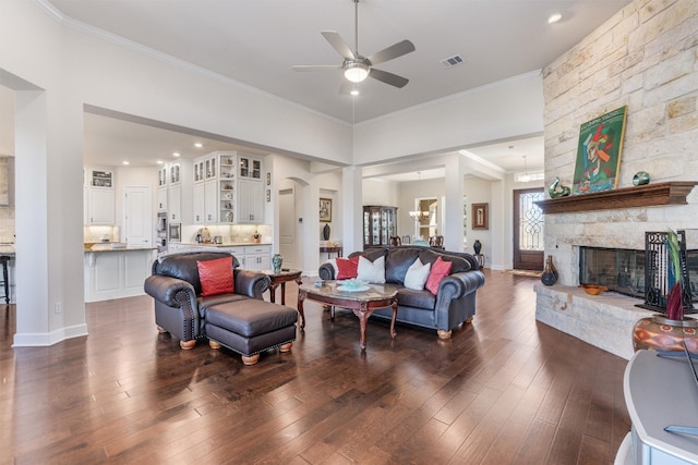 living room featuring a fireplace, dark hardwood / wood-style flooring, ceiling fan, and crown molding