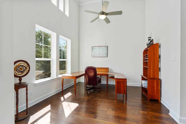 office featuring a towering ceiling, dark hardwood / wood-style flooring, a wealth of natural light, and ceiling fan