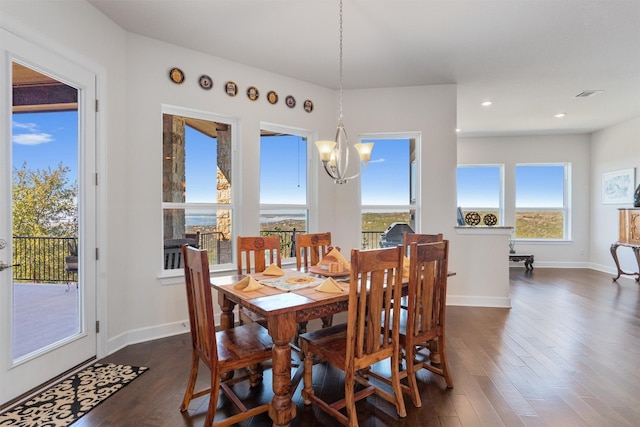 dining space featuring dark hardwood / wood-style flooring, an inviting chandelier, and plenty of natural light