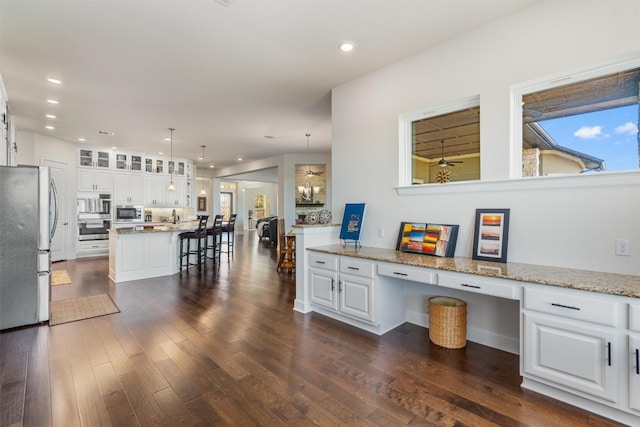 kitchen with pendant lighting, white cabinetry, dark wood-type flooring, and appliances with stainless steel finishes