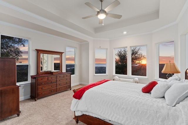 bedroom with a raised ceiling, ceiling fan, light colored carpet, and crown molding