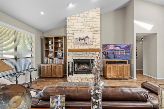 living room featuring light hardwood / wood-style floors, vaulted ceiling, and a fireplace