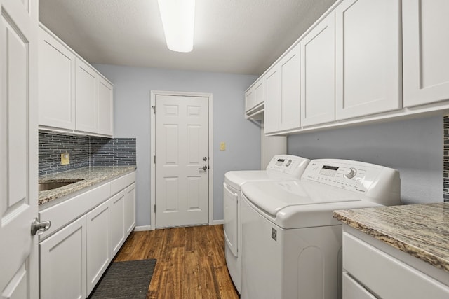 clothes washing area with washing machine and dryer, a textured ceiling, cabinets, dark hardwood / wood-style floors, and sink