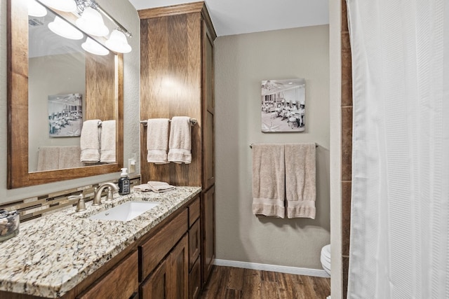 bathroom featuring wood-type flooring, backsplash, vanity, and toilet