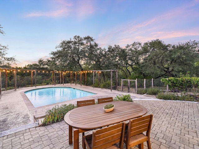 pool at dusk with a patio area