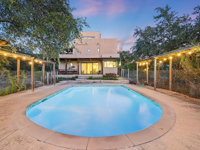 pool at dusk featuring a patio area