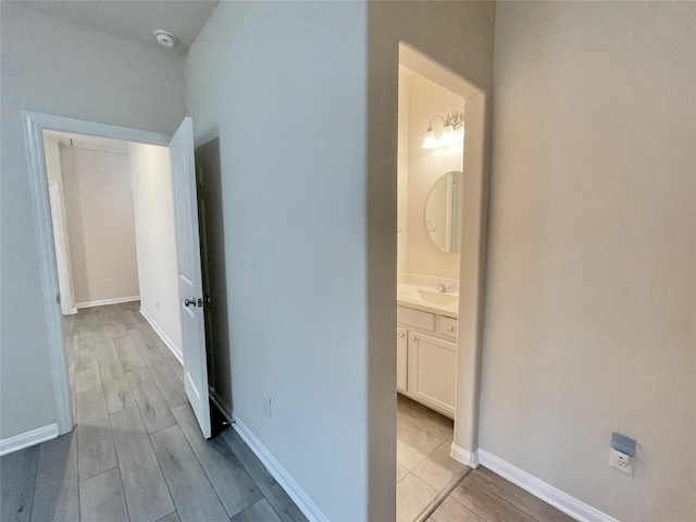 hall featuring sink, a notable chandelier, and light hardwood / wood-style flooring