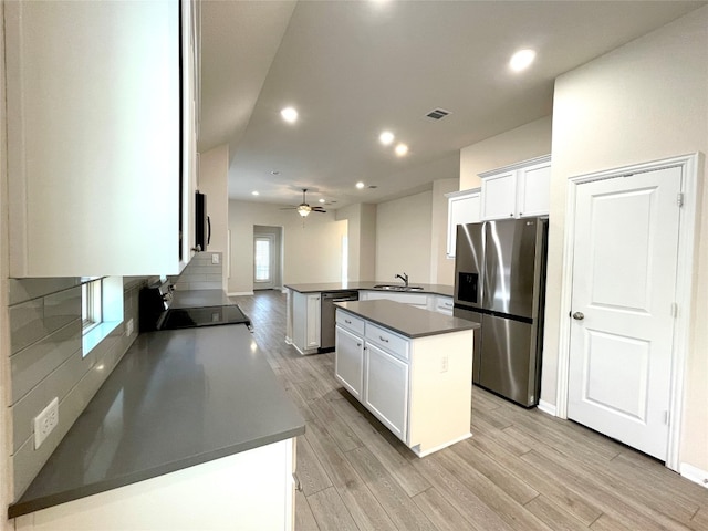 kitchen featuring kitchen peninsula, a center island, white cabinets, and stainless steel appliances