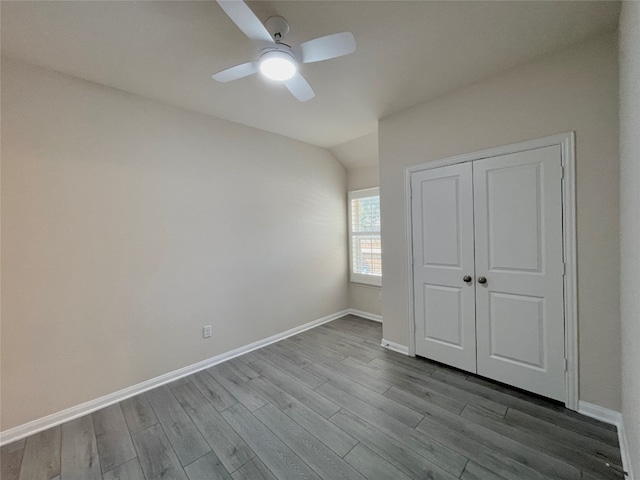 unfurnished bedroom featuring ceiling fan, a closet, light hardwood / wood-style floors, and lofted ceiling