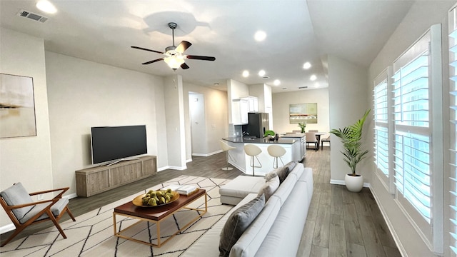 living room with light hardwood / wood-style floors and ceiling fan