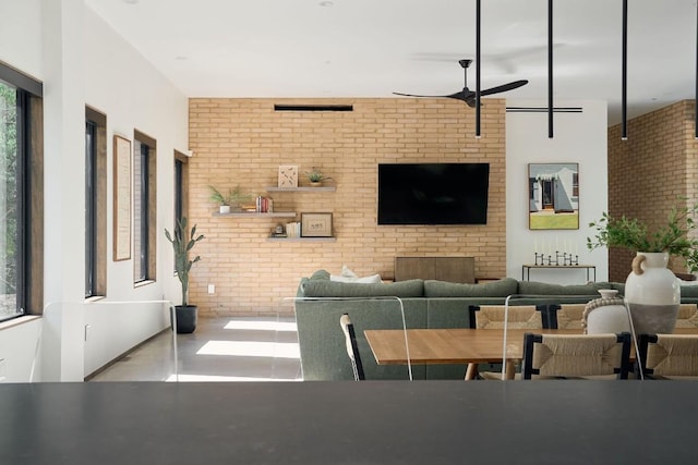 interior space featuring concrete floors, ceiling fan, and brick wall