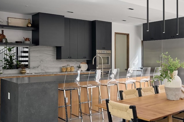 kitchen featuring backsplash, kitchen peninsula, oven, a kitchen bar, and black electric stovetop