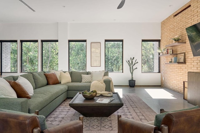 living room featuring plenty of natural light, ceiling fan, and brick wall