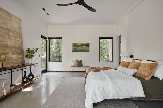 bedroom with multiple windows, ceiling fan, and concrete floors