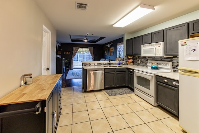 kitchen with kitchen peninsula, ceiling fan, wooden counters, sink, and white appliances